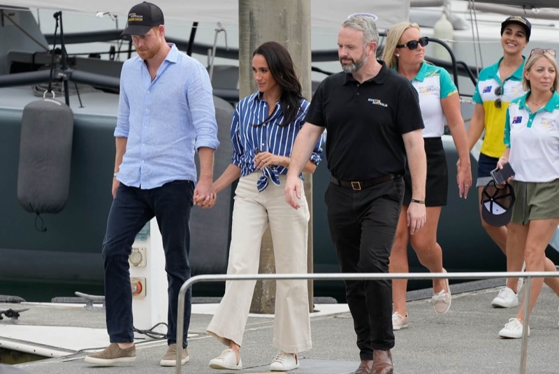 Harry og Meghan hånd i hånd på en brygge
