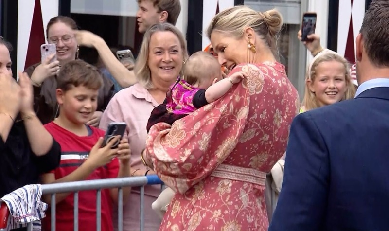 Dronning Máxima holder et lite barn på armen mens folk rundt tar bilder