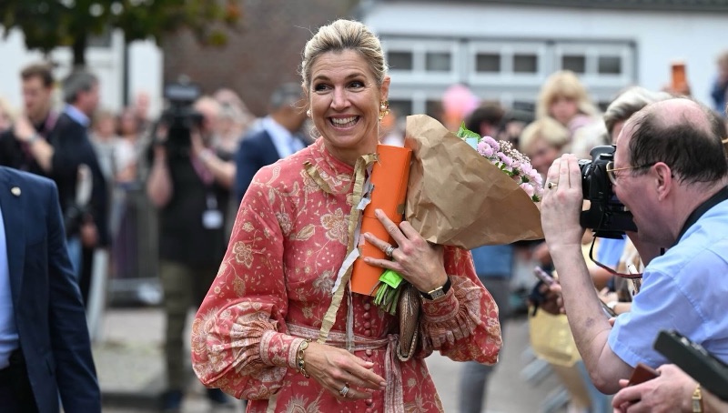 Dronning Máxima ler med en blomsterbukett og en gave i armene