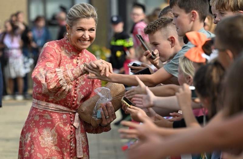 Dronning Máxima smiler og håndhilser på en gruppe ungdommer