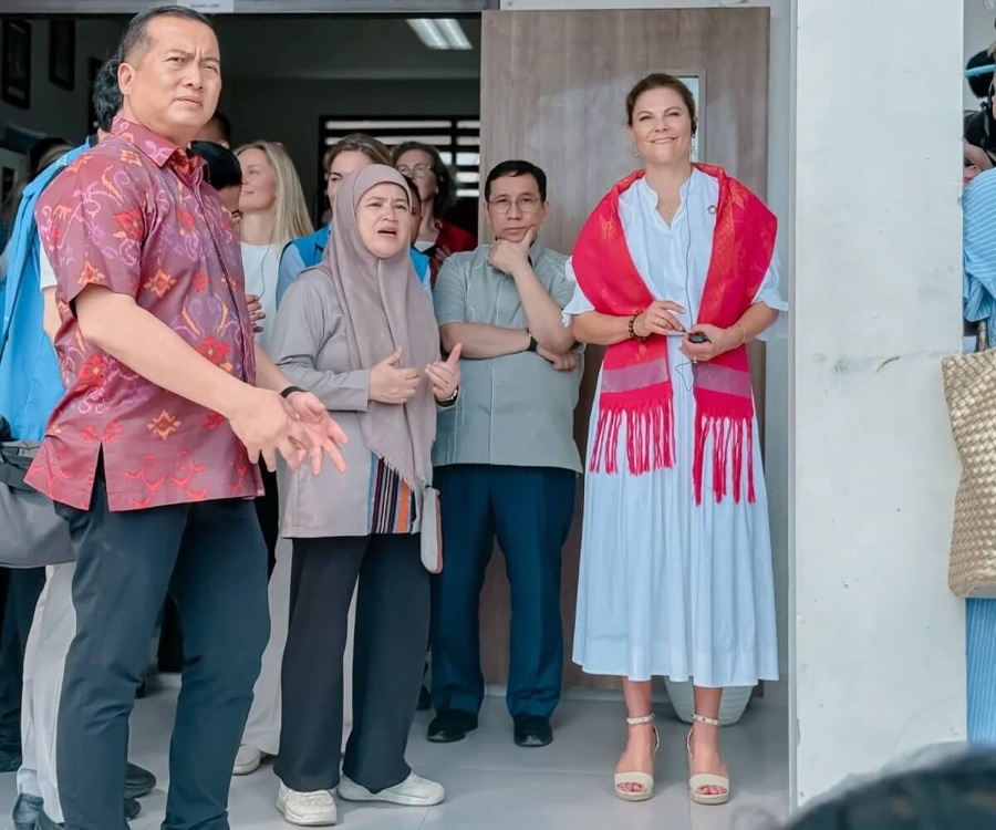 Crown Princess Victoria stands in a doorway together with local representatives during the visit