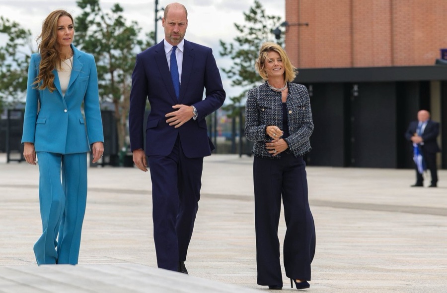 Princess Catherine in a light blue suit walks with Prince William and a woman on the square outside the stadium