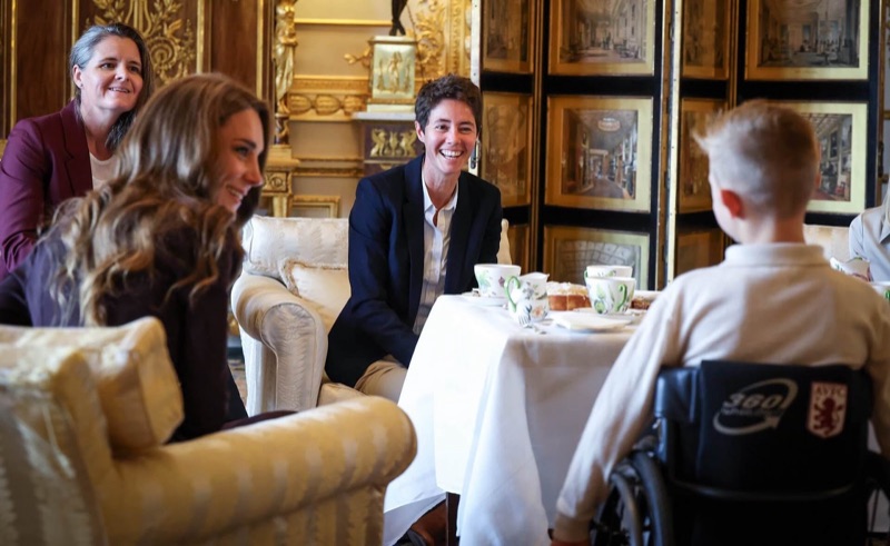 Prinsesse Catherine ler sammen med flere gjester rundt tebordet, med en gutt i rullestol til høyre