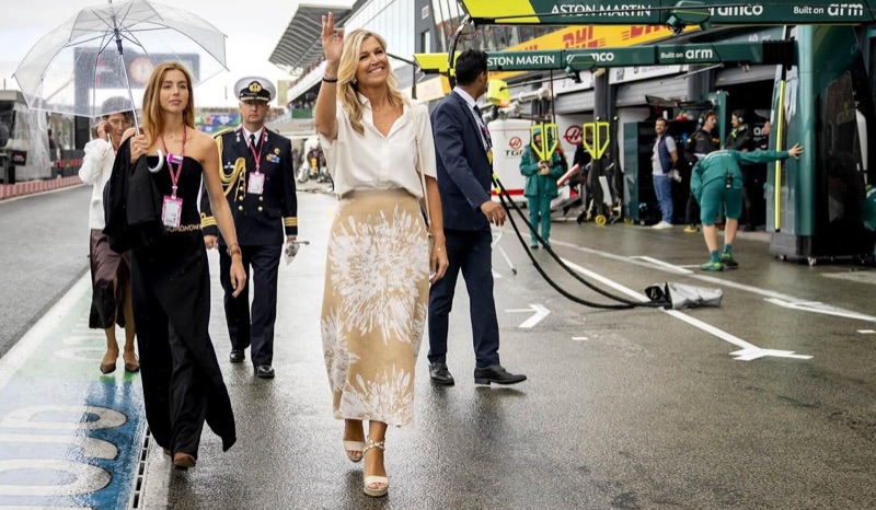 Dronning Máxima vinker i pit lane, med prinsesse Alexia med paraply ved siden